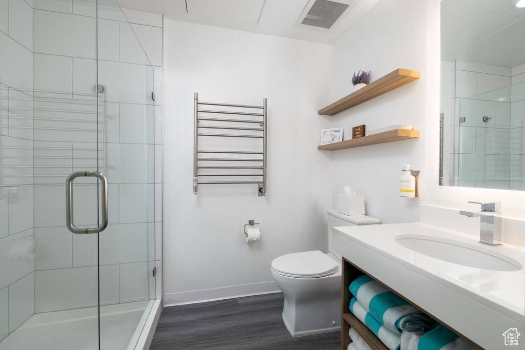 Bathroom featuring vanity, an enclosed shower, radiator heating unit, wood-type flooring, and toilet