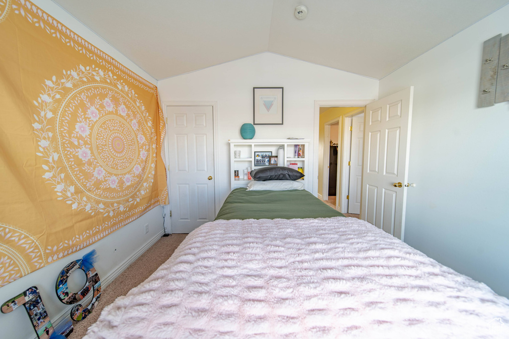 Bedroom featuring light colored carpet and vaulted ceiling