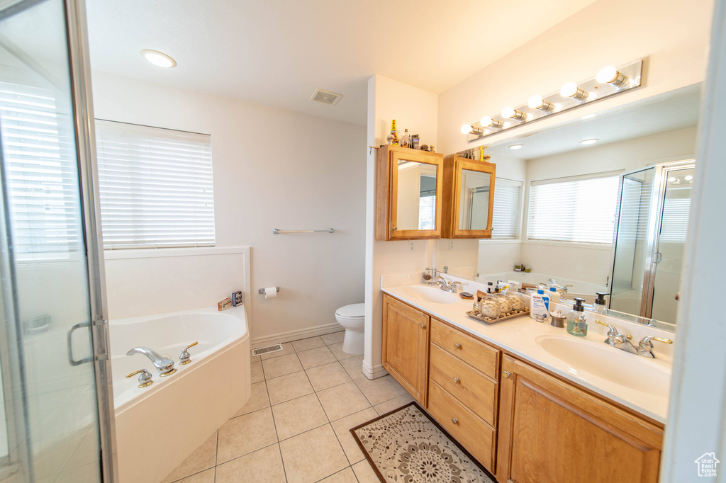 Full bathroom featuring plus walk in shower, double sink, toilet, large vanity, and tile flooring