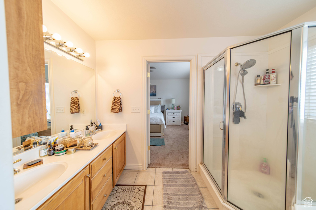 Bathroom featuring a shower with door, dual sinks, tile flooring, and oversized vanity