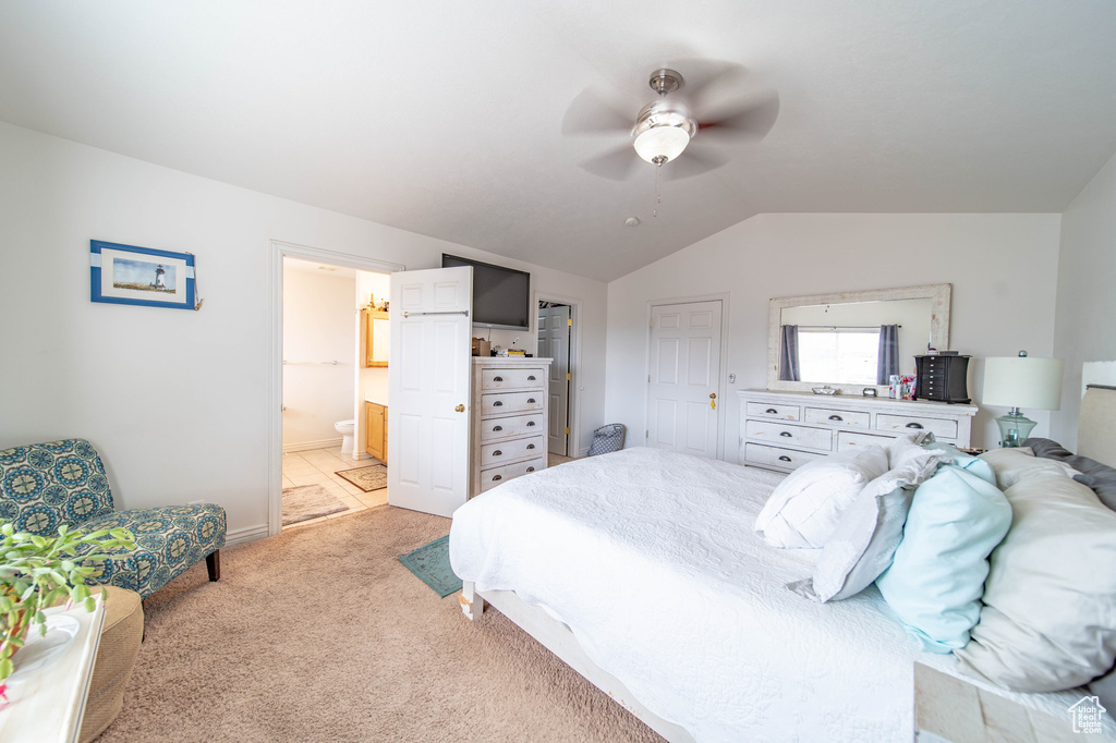 Bedroom featuring ensuite bath, lofted ceiling, ceiling fan, and light carpet