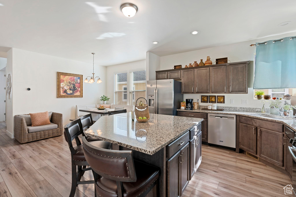 Kitchen featuring a center island, light stone countertops, sink, a notable chandelier, and appliances with stainless steel finishes