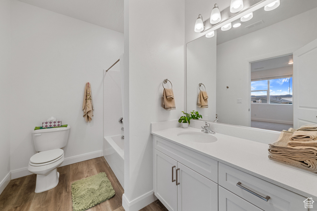Full bathroom with shower / bathing tub combination, hardwood / wood-style flooring, vanity, and toilet