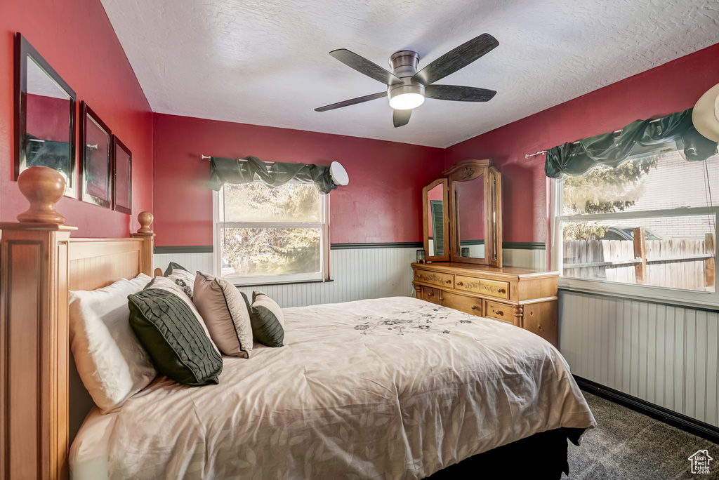 Carpeted bedroom featuring radiator heating unit, ceiling fan, and a textured ceiling