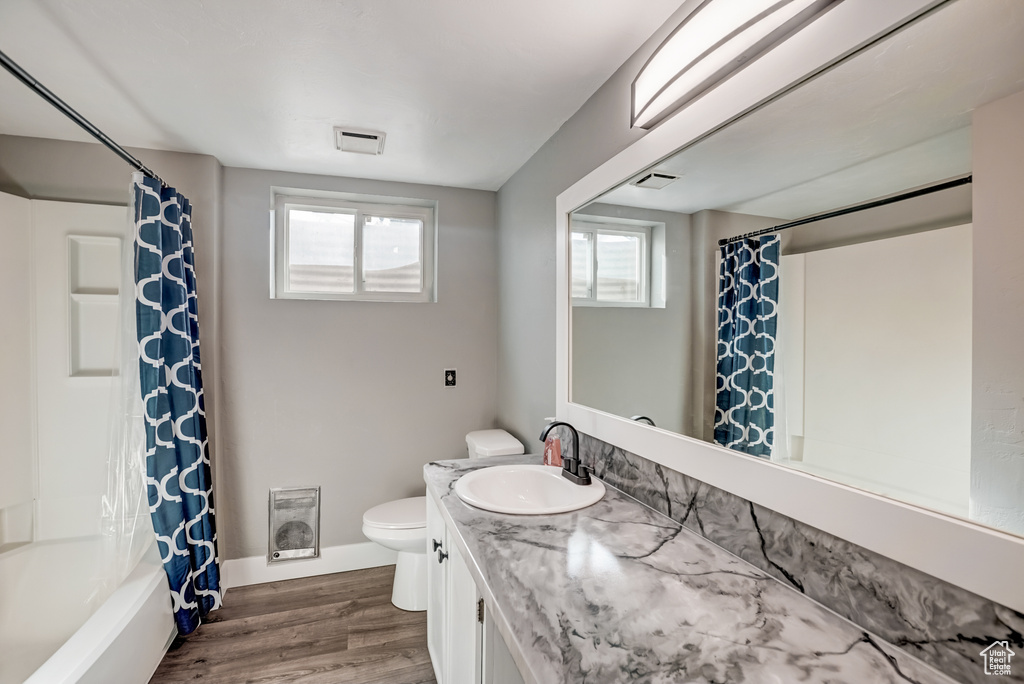 Full bathroom with vanity, toilet, hardwood / wood-style floors, and shower / bath combo with shower curtain