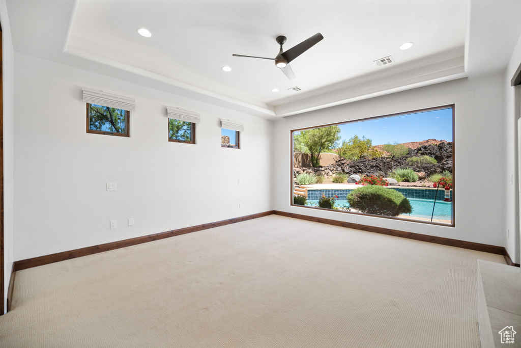 Empty room featuring carpet, ceiling fan, and a tray ceiling