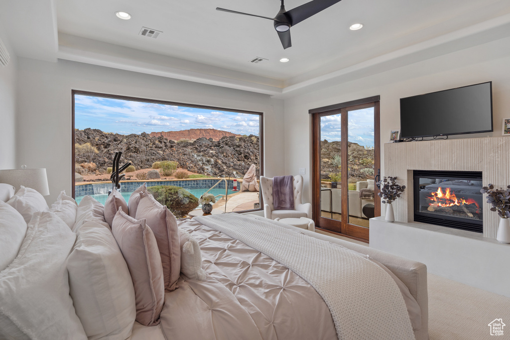 Bedroom featuring a tray ceiling, ceiling fan, and access to outside