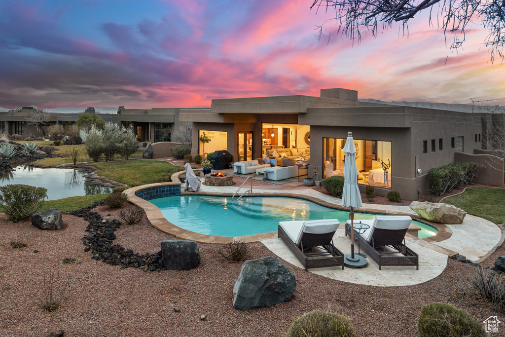 Pool at dusk featuring a yard, a patio, and outdoor lounge area