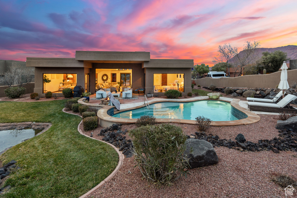 Pool at dusk featuring a patio area and a yard