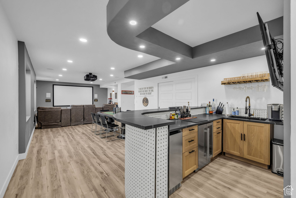 Kitchen featuring light hardwood / wood-style floors, kitchen peninsula, beverage cooler, and sink