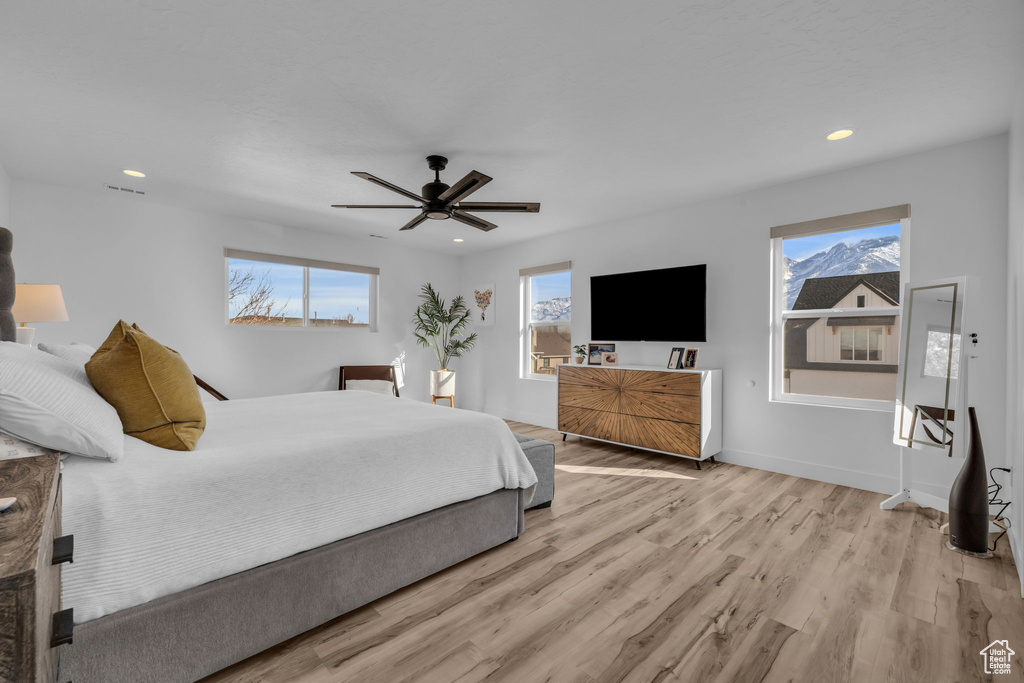 Bedroom featuring multiple windows, light hardwood / wood-style flooring, and ceiling fan