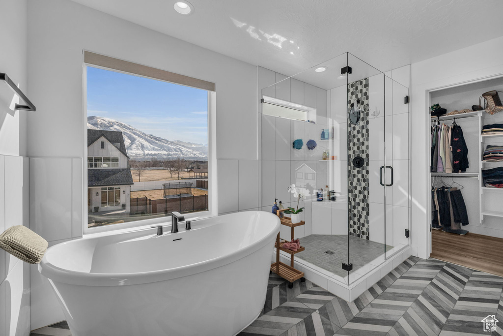 Bathroom with a mountain view, hardwood / wood-style flooring, a healthy amount of sunlight, and separate shower and tub