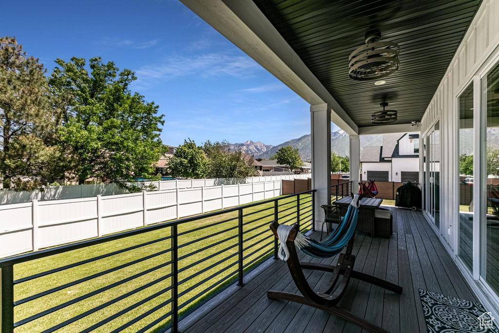 Wooden deck with a mountain view, ceiling fan, and a yard