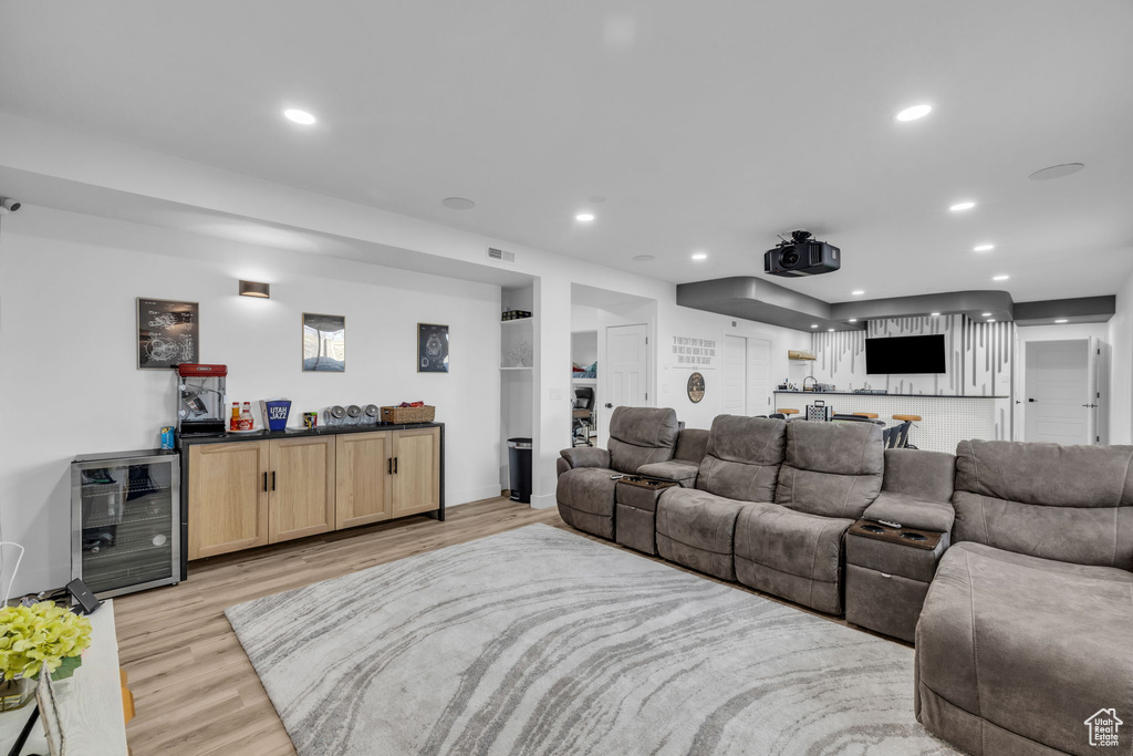 Home theater room featuring light hardwood / wood-style floors and beverage cooler
