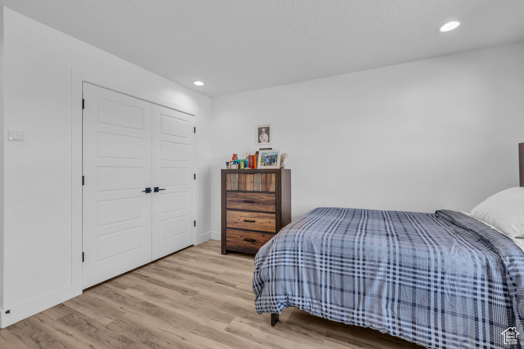 Bedroom with light hardwood / wood-style flooring and a closet
