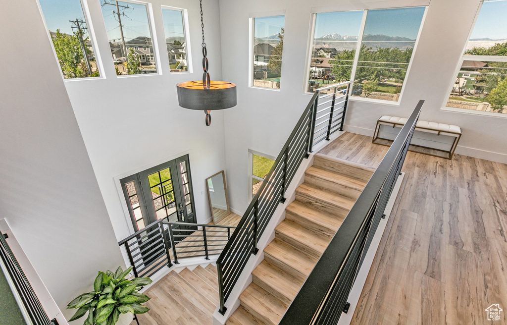 Stairs featuring a wealth of natural light, light hardwood / wood-style flooring, and a towering ceiling