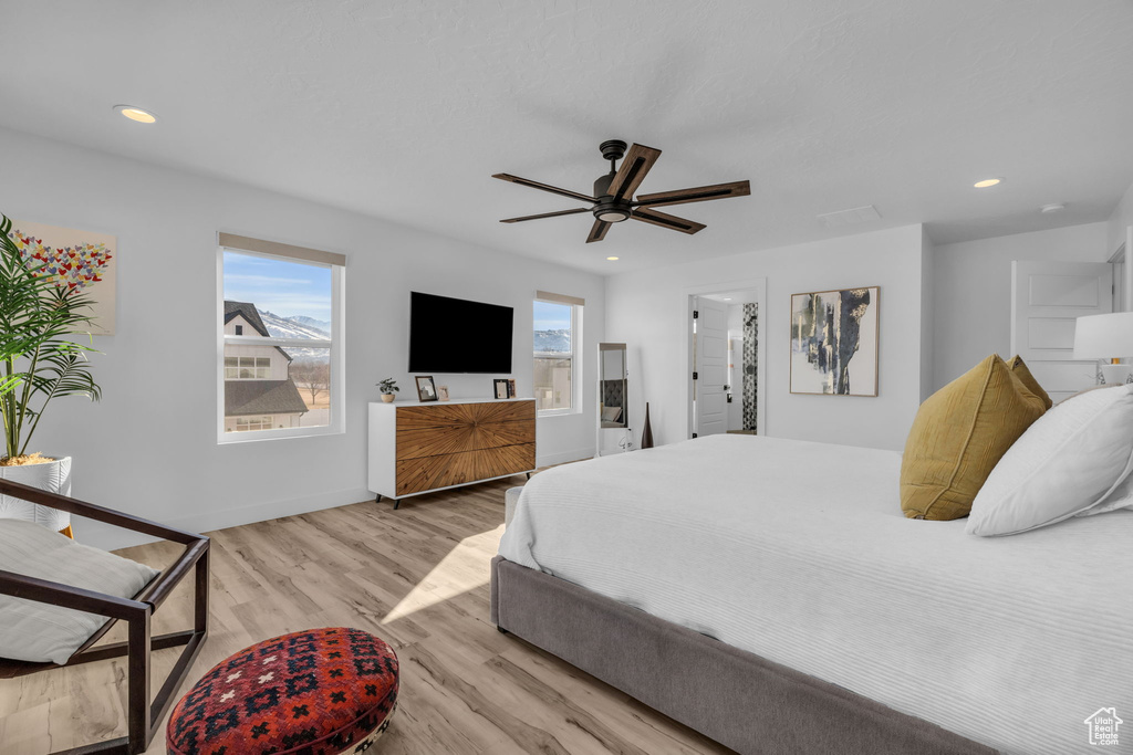 Bedroom with light hardwood / wood-style flooring, ceiling fan, and connected bathroom