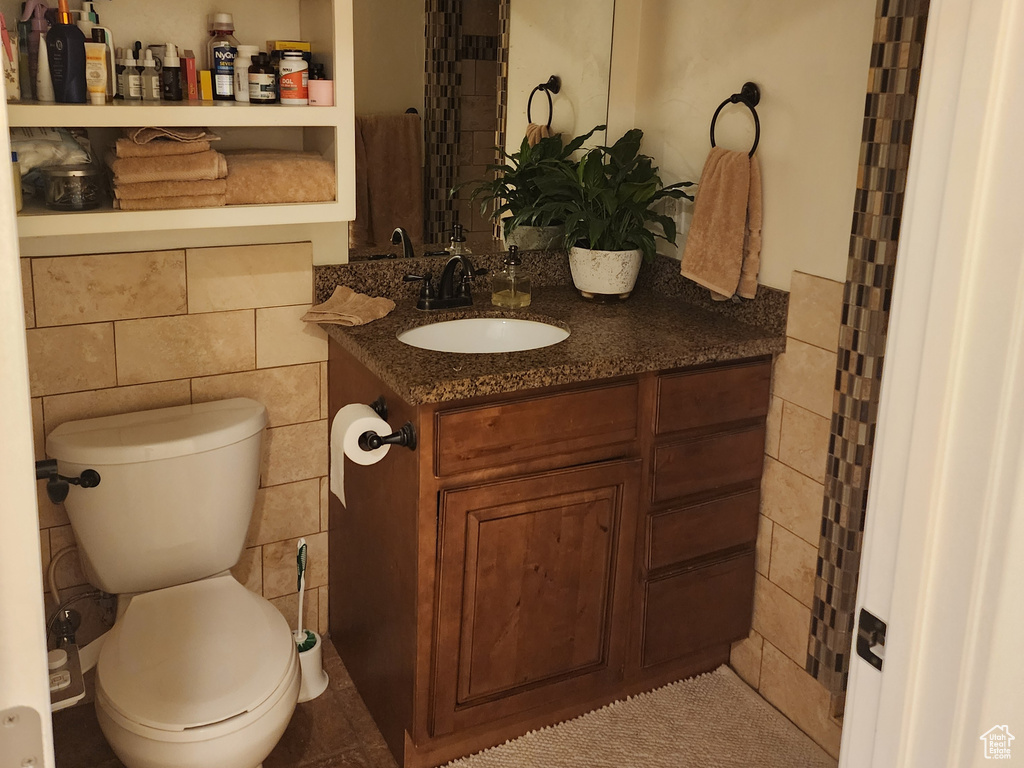 Bathroom featuring toilet, tile floors, and vanity with extensive cabinet space