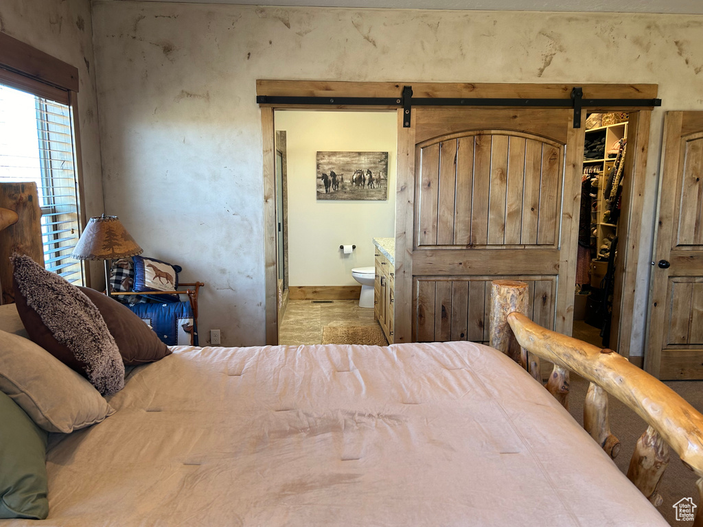 Bedroom featuring ensuite bath, a walk in closet, a closet, and a barn door