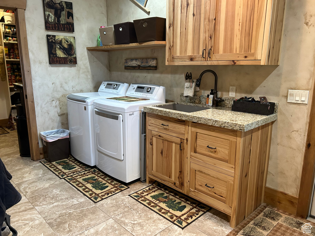 Laundry room with light tile flooring, cabinets, washing machine and dryer, and sink