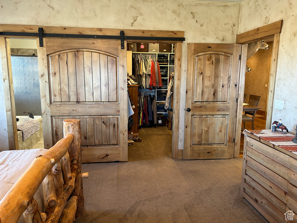 Bedroom with a spacious closet, a barn door, carpet flooring, and a closet
