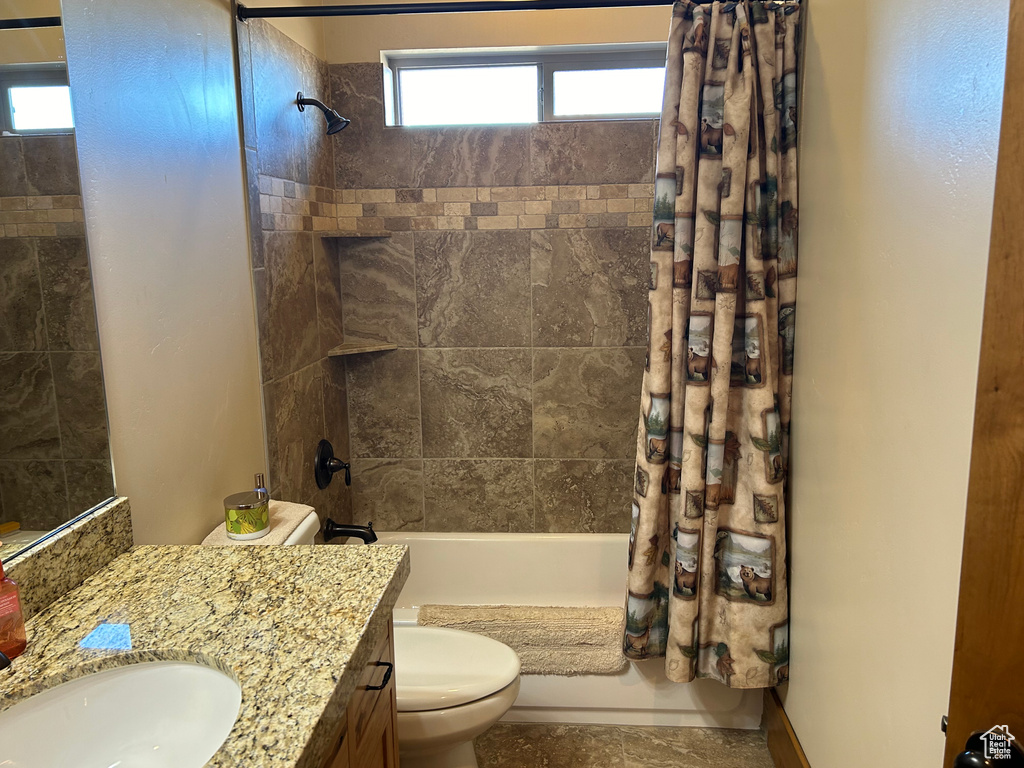 Full bathroom featuring shower / bath combination with curtain, vanity with extensive cabinet space, and toilet