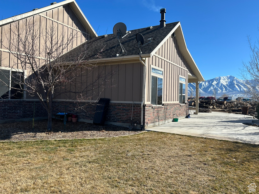 View of home\\\'s exterior featuring a lawn, a patio, and a mountain view