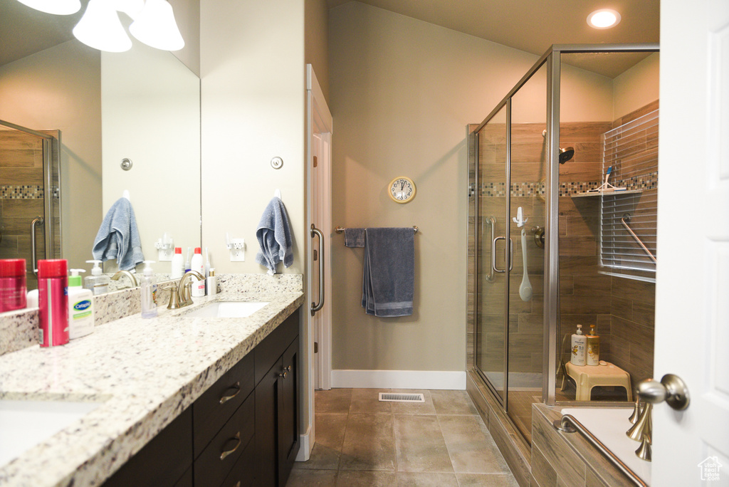 Bathroom featuring double sink vanity, tile floors, and walk in shower
