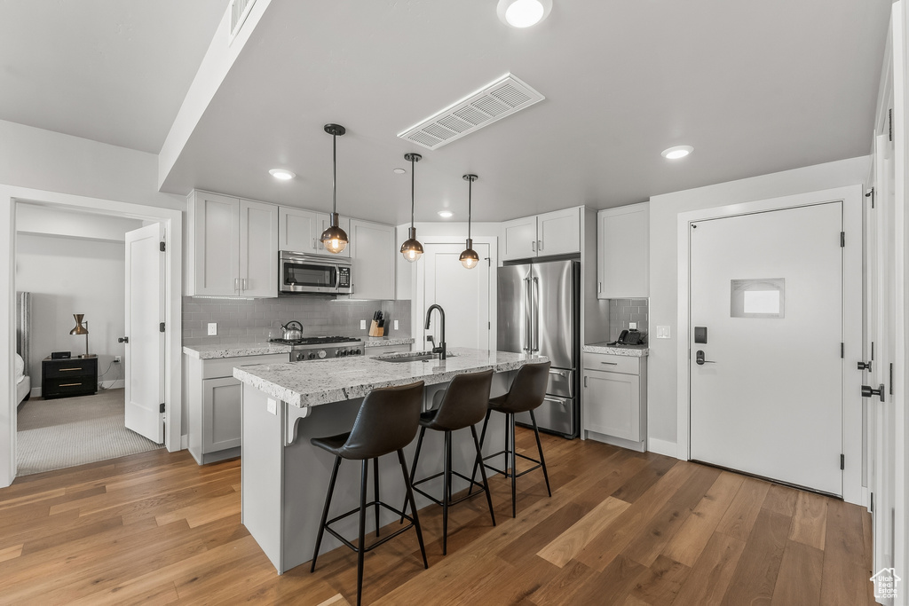 Kitchen with light carpet, tasteful backsplash, appliances with stainless steel finishes, sink, and decorative light fixtures