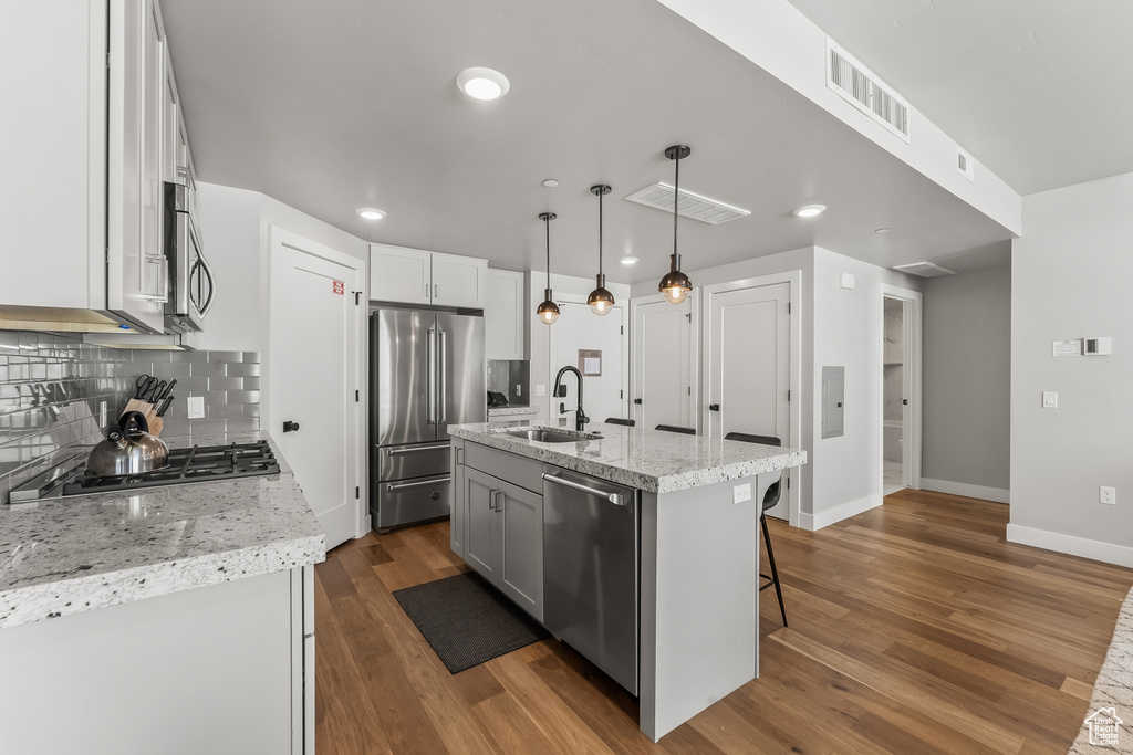 Kitchen with backsplash, hanging light fixtures, dark hardwood / wood-style floors, sink, and appliances with stainless steel finishes