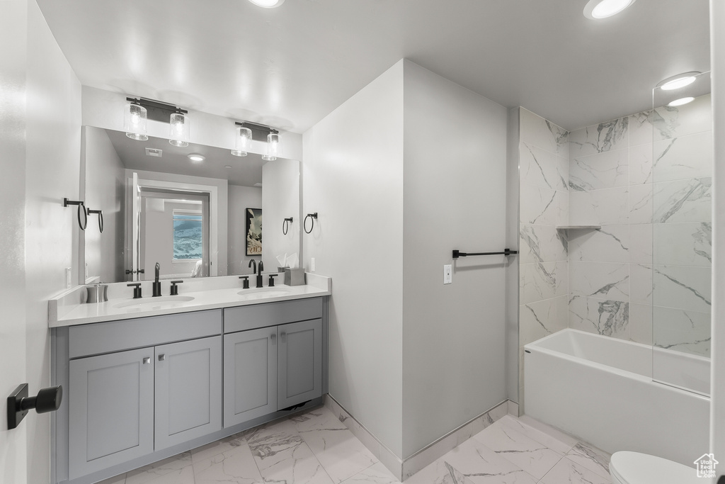 Full bathroom with tile floors, tiled shower / bath combo, double sink vanity, and toilet