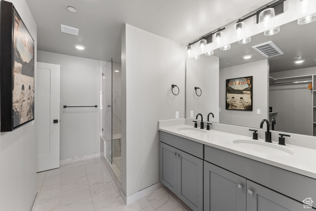 Bathroom featuring an enclosed shower, double sink, vanity with extensive cabinet space, and tile flooring