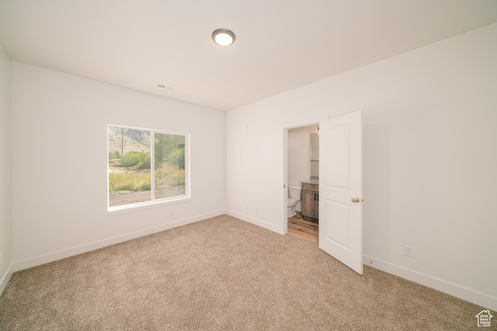Unfurnished bedroom with light colored carpet and ensuite bathroom
