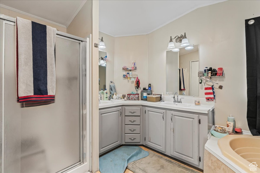 Bathroom with large vanity, double sink, ornamental molding, and separate shower and tub
