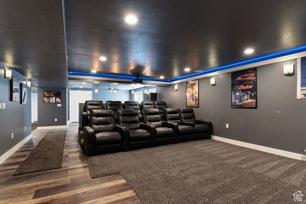 Cinema with dark hardwood / wood-style flooring, a tray ceiling, and ceiling fan