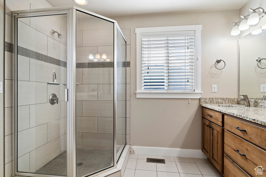 Bathroom featuring walk in shower, tile floors, and vanity with extensive cabinet space