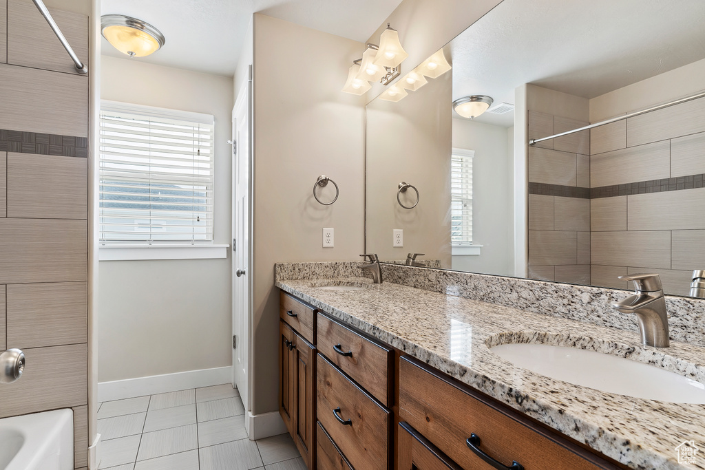 Bathroom with a wealth of natural light, double vanity, tiled shower / bath combo, and tile flooring