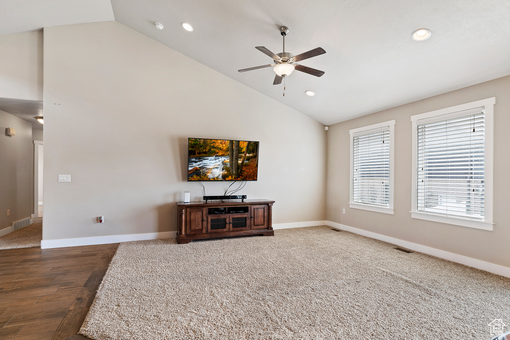 Living room with high vaulted ceiling, ceiling fan, and dark carpet