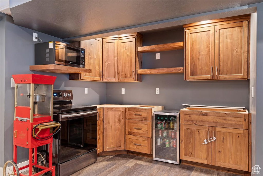 Kitchen with dark hardwood / wood-style floors, range with electric cooktop, and beverage cooler