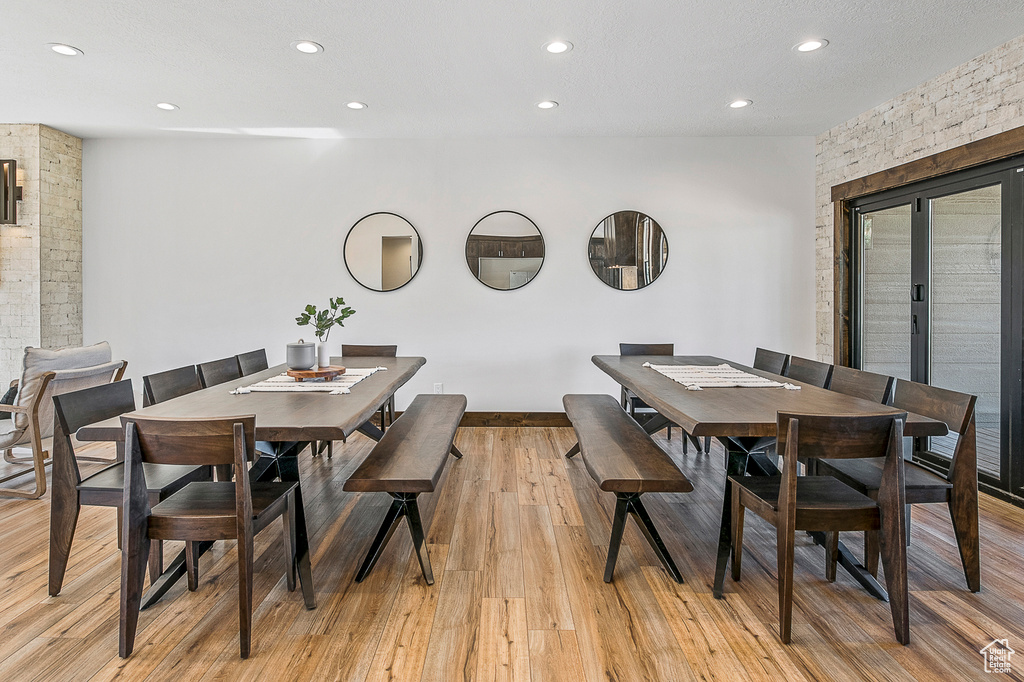 Dining room with brick wall and light hardwood / wood-style floors