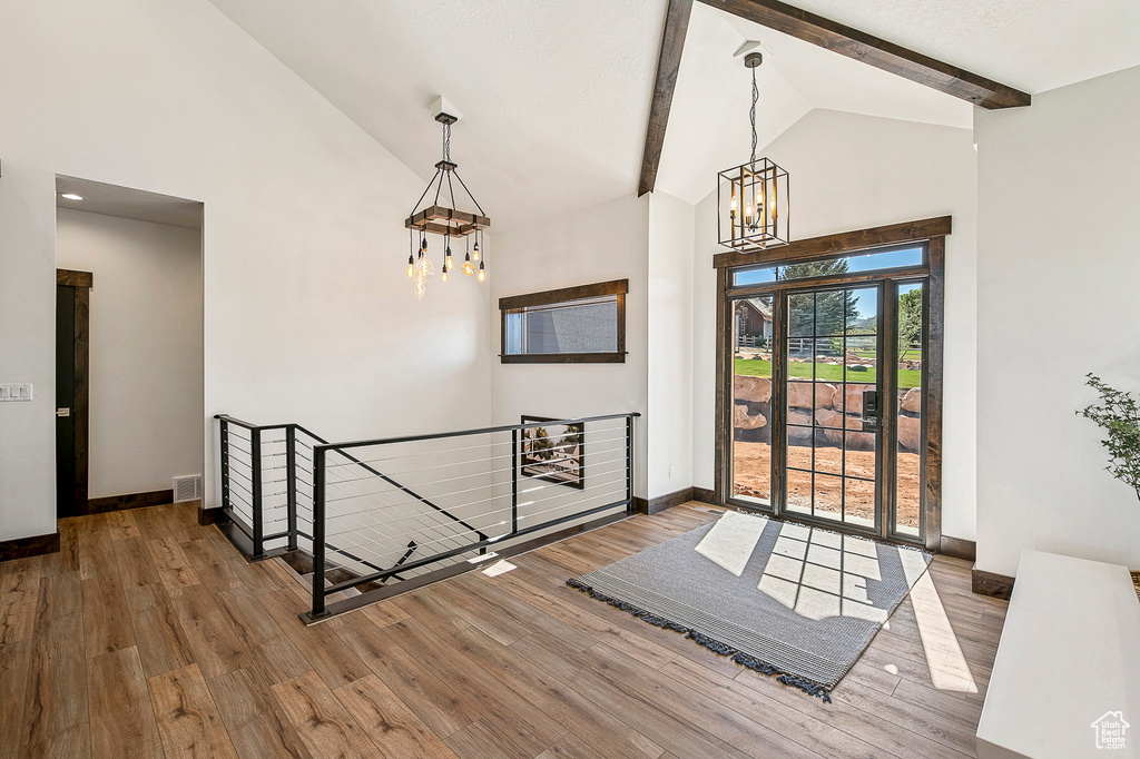 Entrance foyer with dark hardwood / wood-style floors, beam ceiling, high vaulted ceiling, and an inviting chandelier