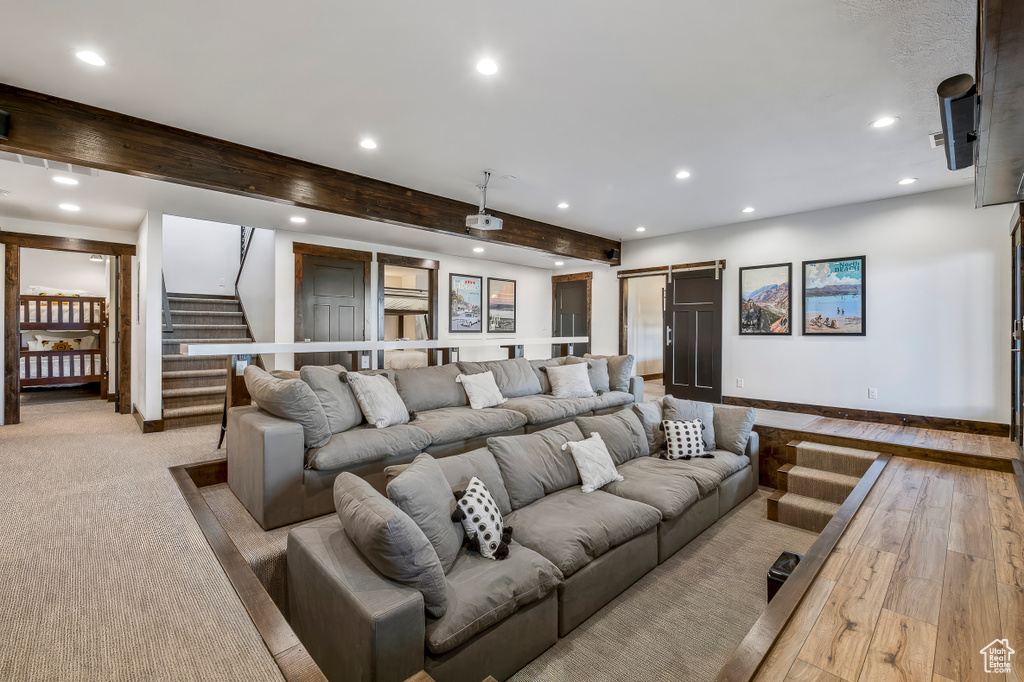 Home theater with light hardwood / wood-style flooring, beam ceiling, and a barn door