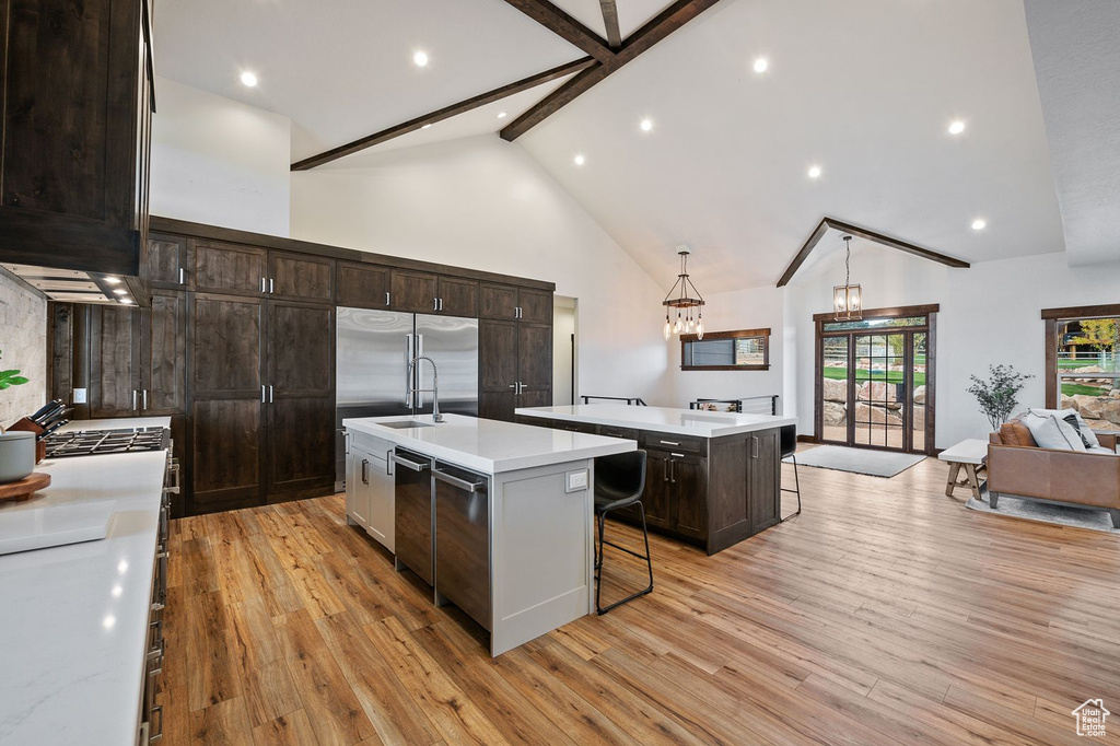 Kitchen featuring a breakfast bar area, high vaulted ceiling, a center island with sink, and light hardwood / wood-style floors