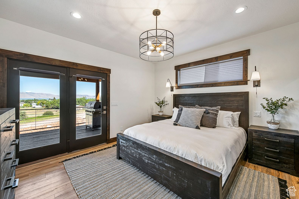 Bedroom with a chandelier, light hardwood / wood-style flooring, and access to exterior