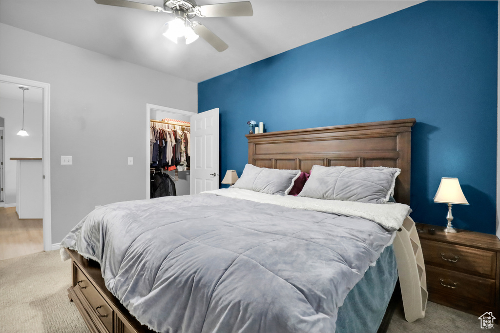 Bedroom featuring a spacious closet, a closet, ceiling fan, and light carpet