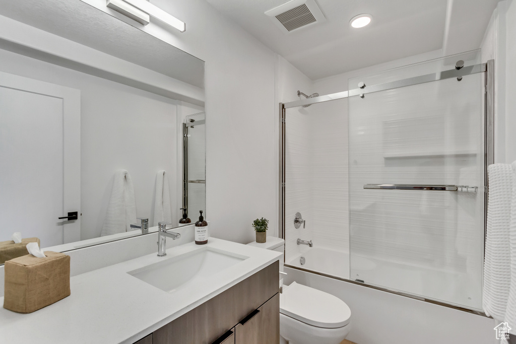 Full bathroom with vanity, shower / bath combination with glass door, and toilet