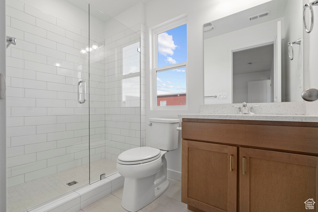 Bathroom featuring a shower with shower door, tile flooring, oversized vanity, and toilet