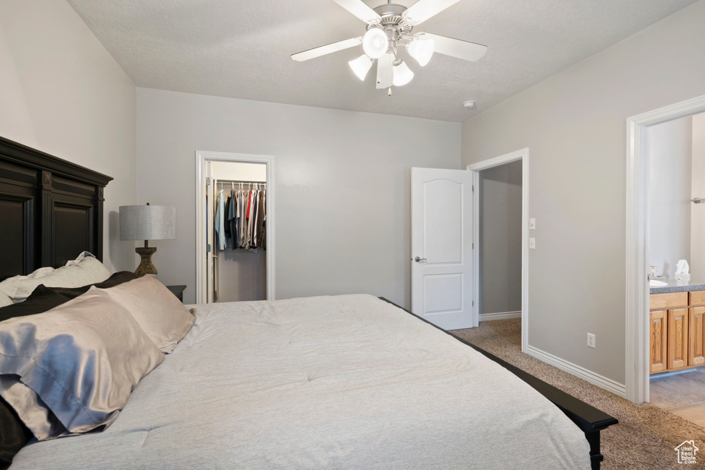 Bedroom with connected bathroom, ceiling fan, a closet, a walk in closet, and light colored carpet