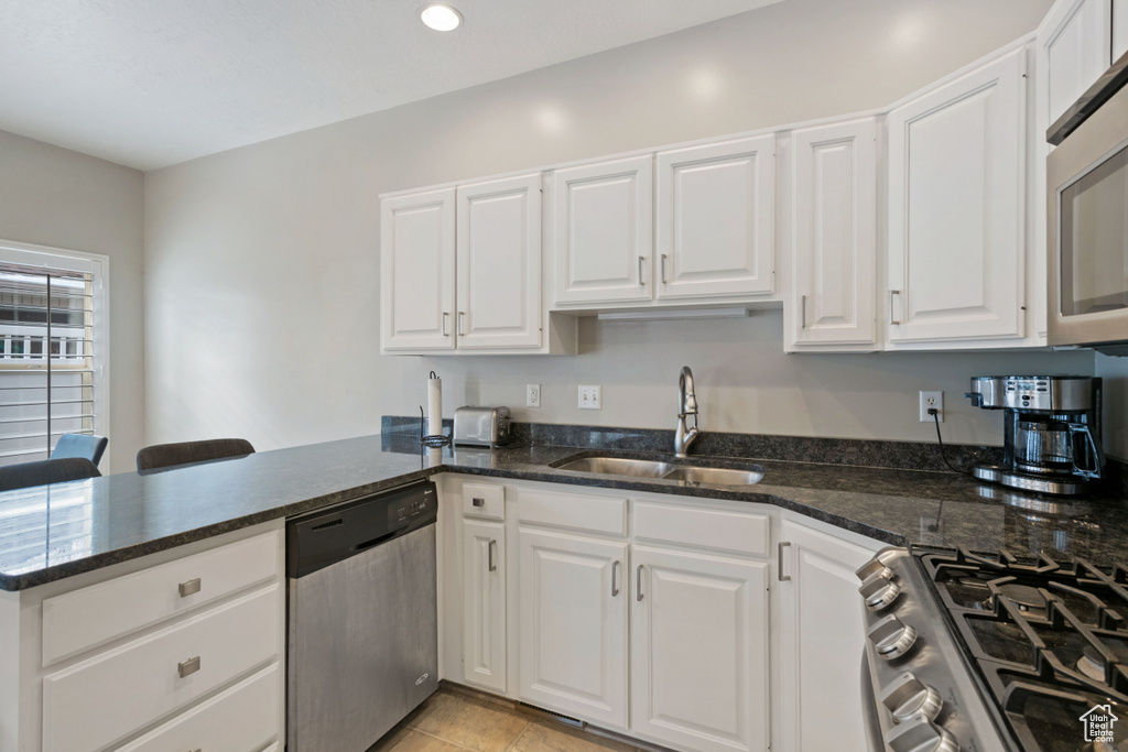 Kitchen with white cabinetry, sink, stainless steel appliances, and kitchen peninsula