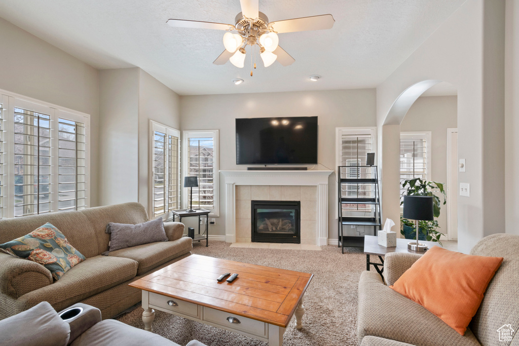 Carpeted living room featuring a fireplace and ceiling fan